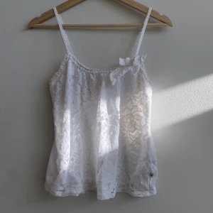 Hollister linne - Sommarlinne från Hollister med spetsdetaljer 💘 I storlek XS men passar även S. Fint skick men tecken på användning 💞 Justerbara band och en söt rosett vid vänster ”Axel” 💘 Bara höra av sig vid frågor, köparen står för frakten 💞