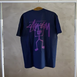 Stussy tröja - En mörkblå stussy tröja med stort lila tryck på ryggen. Storlek large