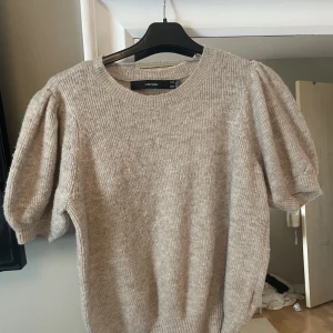 Beige stickad t-shirt - Jag säljer denna fina stickade beiga t-shirten med puff-ärmar. Den är använd några gånger men fortfarande fint skick på den.