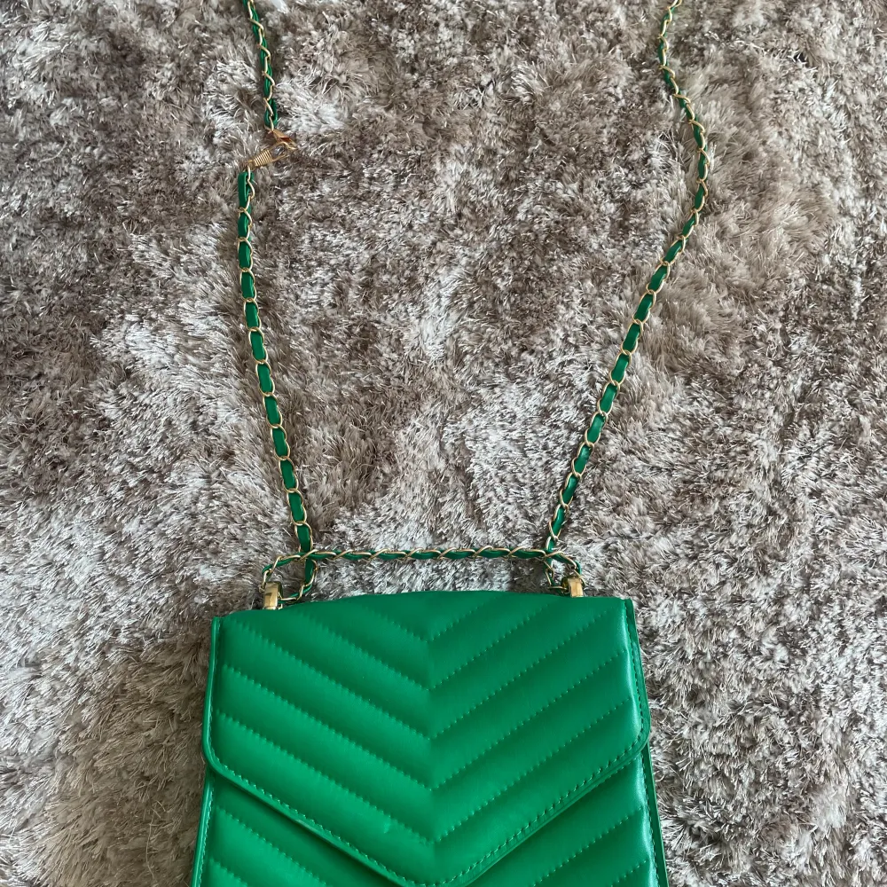 Oanvänd grön handväska med gulddetaljer. Väskor.
