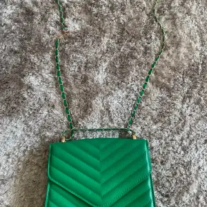 Oanvänd grön handväska med gulddetaljer