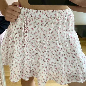 Vit kjol med rosa blommor - Vit kjol med rosa blommor. Aldrig använt. Det är storlek S på kjolen men den passar för S/M. Perfekt sommarkjol