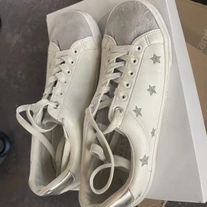 Vita sneakers med stjärnor - Next sneakers köpta på zalando för 600kr. Skorna är använda ett fåtal ggr men på den ena skon har mockan blivit vattenskadad, därav det billiga priset. Produkten är slutsåld på hemsidan💓