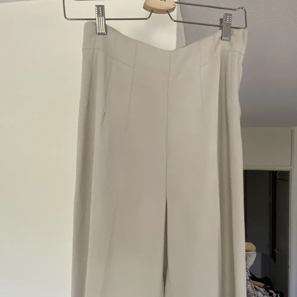 Vita/grå, långa, vida kostymbyxor med pressveck. Aldrig använda. . Jeans & Byxor.