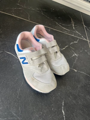 New Balance 34 - New Balance i storlek 34.  Ljusbeige färg, dova färger. Finns tecken på användning. Kan maskintvättars.  Skickas mot portokostnad. 
