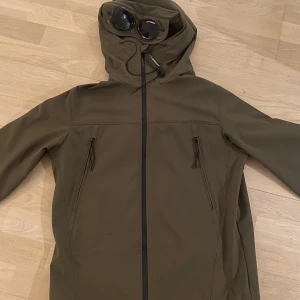 Cp company jacka Shell-R - Säljer nu min mörk gröna cp company  jacka. Den är i väldigt bra skick och knappt även förutom en brännskada på luvan. Det är ett väldigt  litet håll däremot har det blivit lite svart runt det. Jackan är i storlek 50 och motsvarar ish Large. Nypris: 4500