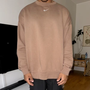 Nike tröja sweatshirt  - Nike sweatshirt i bra skick.  Oversized så stor i storleken jag är 180cm 72kg. Den är mer som en L än S som det står på lappen.  Ljusbrun med en vit broderad nike swoosh i mitten fram.  För stor för mig så har knappt använt. 80% bomull 20% polyester.