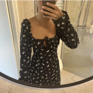 Svart klänning - Svart klänning från hm med små blommor. Använd en gång. Säljer pga för tight i midjan. 