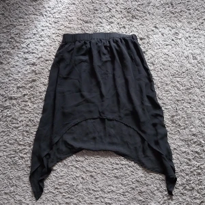 Svart kjol.  - Mellanlång svart kjol. Kjolen slutar innan knäna men är längre på sidorna. Köpt på hm. Nyskick.   Betalning sker via swish. Köparen står för frakten.