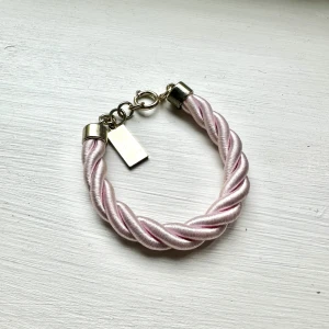 Rosa flätat armband - Rosa flätat armband, köpt på Lindex för att stötta bröstcancerfonden. 