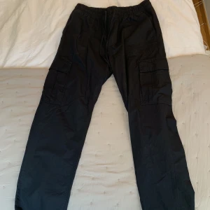 Cargobyxor - Svarta fina cargobyxor från Weekday i storlek L. Byxorna har en ganska lös passform och lägger sig fint över skorna (192cm lång). Sparsamt använda! 