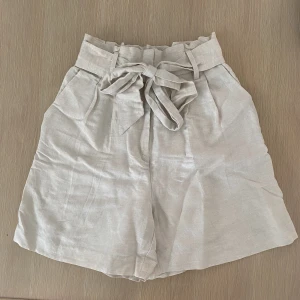 Beiga linneshorts - Beiga högmidjade linneshorts med justerbart band/knyte i midjan från H&M i storlek 38. Enbart provade och aldrig använda🤎