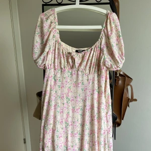 Blommig klänning BikBok - Blommig klänning från BikBok i storlek L, med kortare underkjol och en slit på sidan. I väldigt bra skick, endast använd en gång! Kan både posta och träffas upp i Stockholm :)