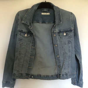 Jeansjacka i stl M. - En fin blå jeansjacka. Jackan är aldrig använd och i nytt skick. Jackan är perfekt för både vår och höst och är i stl M.