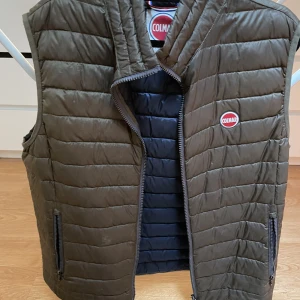 Colmar väst - Colmar väst i strl 54, mörk bronz färgad skulle jag säga, kan tyckas skifta till något brunt/grönt i en mörkare nyans. Inga skador eller liknande, utan i perfekt skick. Väldigt tunn så funkar perfekt under kyligare dagar/kvällar under sommaren