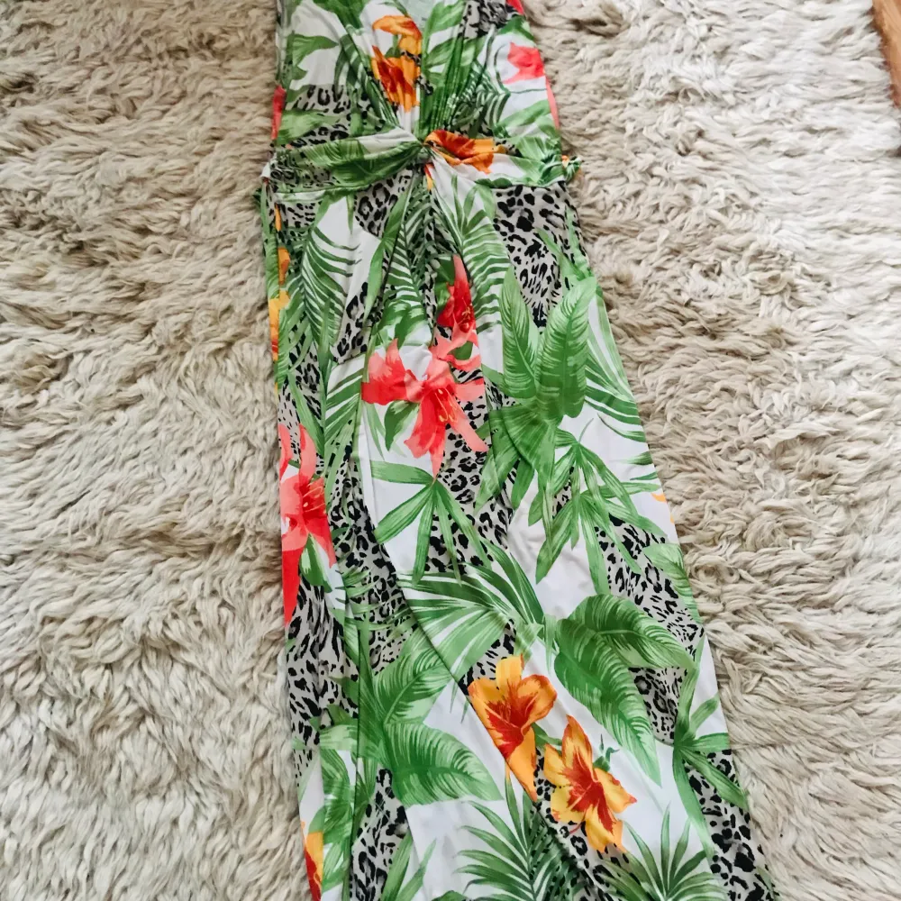 En färgstau festklänning med stora underbar🌺 blommor 🌺 och 🌿blad. One Size passar S-M  (har smören runt midjan)  . Klänningar.