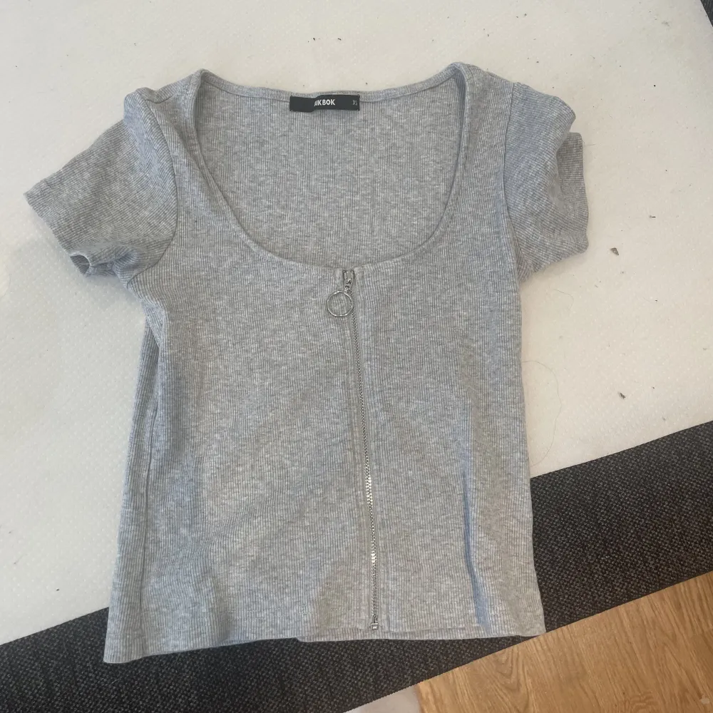 En grå T-shirt med dragkedja fram, från Bikbok i storlek XS.  Minns inte sist det användes men den är bara använd några få gånger för möjligtvis 1-2 år sedan annars har den bara legat i lådan.  Kan tvättas innan den skickas/hämtas . T-shirts.