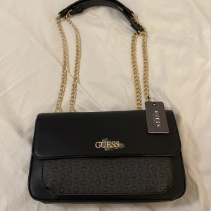 Guess väska - Väska från Guess i nyskick med prislapp på. Väskan är äkta och går att scanna genom Qr kod. 