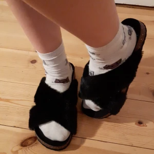 Svarta tofflor - Säljer för att de ej kommer till användning. Banden som går över tårna är gjort i ett fluffigt material och är päls. Väldigt bekväma. Kontakta mig vid frågor. Köparen står för frakten!