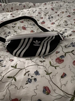 Adidas midjeväska  - Säljer min adidas midjeväska då jag aldrig använder den! Perfekt att ta me överallt, enkel och liten få du slipper ha med en stor ryggsäck överallt! Den är liten men kan hålla de mesta!