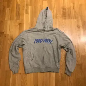 Säljer min gråa Fred perry zip up hoodie då den är lite för liten för mig, den är i perfekt skick och har ett coolt tryck i graffiti stil. Skriv för fler bilder:kr