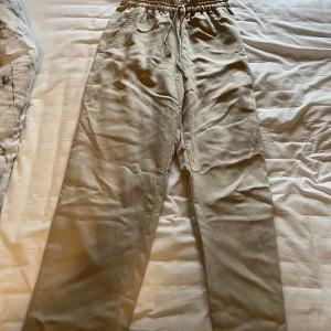 Byxor - Beiga bekväma byxor köpta på H&M. Använda varsamt under förra sommaren. Som nya. Inga defekter. Tyget är likt silkestyg utanpå men fortfarande hyfsat tjockt tyg. Skriv i DM vid frågor. Köparen står för frakten 