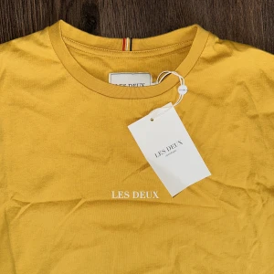 T-shirt  - Helt ny och oanvänd T-shirt från Les deux.   Rensar ur min garderob från en hel del oanvända kläder🌼 Kika och se om du ser något mer i min profil som du gillar så skickar jag med det till dig också!😊 Fler kläder kommer! 