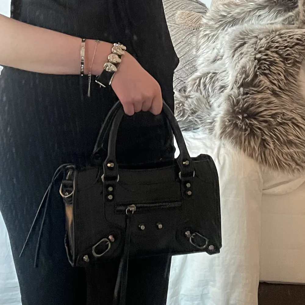 En svart liten Balenciaga liknande väska! Helt oanvänd, så därav mycket fint skick <3 Medföljer långt axelremsband . Väskor.
