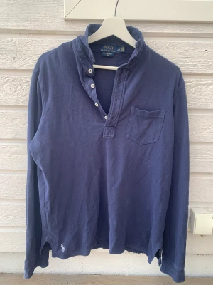 Blå Ralph Lauren tröja  - Långarmad blå pikétröja, Ralph Lauren. Märket sitter på nedre delen av tröjan.
