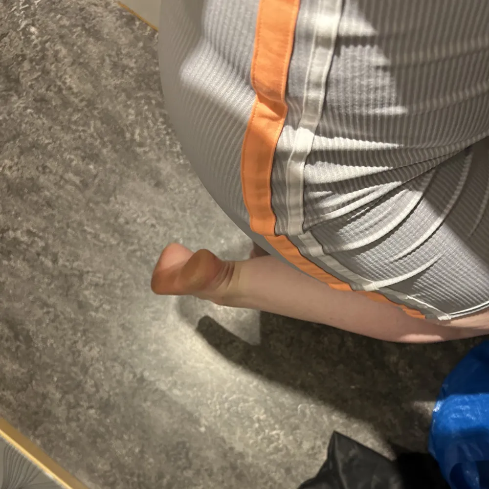 En silvrig kortare klänning från hm med orangea och vita sträck längs sidorna i strl M som aldrig är använd. Klänningar.
