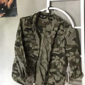 Militärmönstrad kofta - Sparsamt använd pullover tröja i militärstil med diskreta nitar