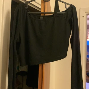 Svart topp  - En svart topp med axelrem som syns på bild två