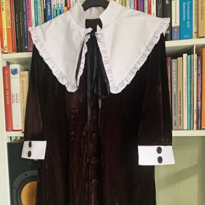 Lolita Cosplay - Ouji Lolita klädnad i storlek M! Består av en button up (längd: 81cm. Bredd: 47cm, stretchigt material), beiga byxor (längd: 70cm) med resårband samt rosett på vardera nedre byxben, till sist ett svart band.   Använd endast en gång.  Material: polyester.