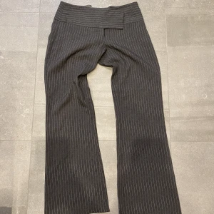 Y2k kostymbyxor lågmidjade bootcut - Lågmidjade kostymbyxor i bootcut modell. Nån knapp har gått av med går att stänga utan att det ser konstigt ut ändå. Passar strl S/36 i midjan och någon som är 155-165 cm lång. Annars fint skick på byxan och från vintage märke!!