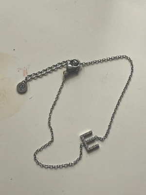 Armband Edblad - Ett jättefint armband från Edbland med intialen E på. Knappt använt och i fint skick på både bokstaven och kedjan. Köpt för 349kr