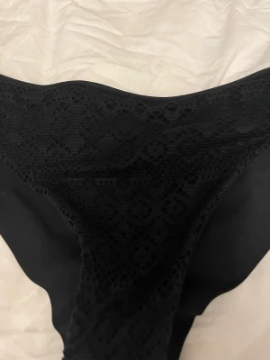 Bikini underdel - Svart bikiniunderdel med mönster på fram sidan.