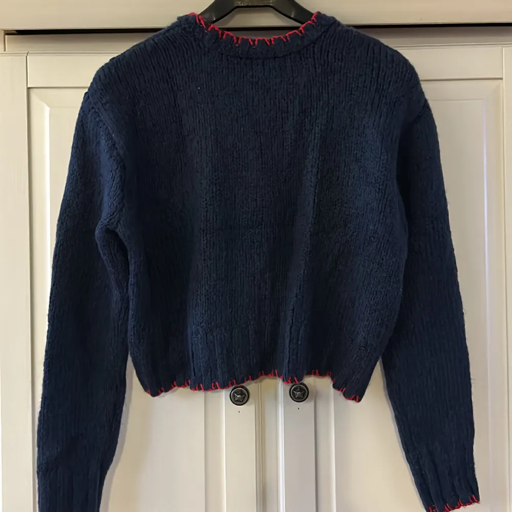 En kortare stickad tröja från zara i färg marinblå med röda detaljer, storlek S. Stickat.