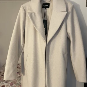 Beige Kappa - Beige kappa köpt från Nelly. Aldrig använd. Medellång, ner till knäna. Jättebra skick. Ordinarie pris 799kr. Pris kan diskuteras vid snabb affär.