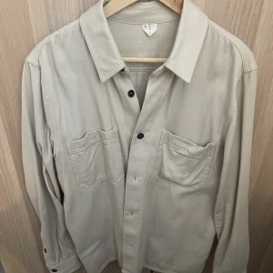 Skjorta Arket - Lite tjockare vit/beige skjorta från arket, fint skick men finns en liten liten fläck på kragen som förmodligen går bort i tvätten! Använd en handfull gånger. 