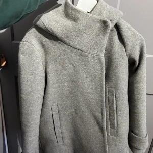 Kort kappa - Kort kappa med liten luva. Knappatängning. Fint men använt skick. Kan skicka bilder på om det önskas!