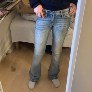 Lågmidjade blåa jeans med slitningar  - Säljer ett par skitsnygga lågmidjade jeans med slitningar från Crocker i storlek 26/31. Köpte dem på sellpy men har inte andvänt själv då dem tyvär var för små. bilderna med byxorna på min syster som är 1,62