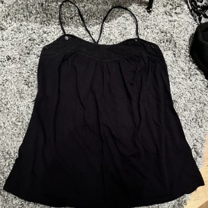 svart linne 🖤 - svart utsvängt linne med mönster upptill och korsade band bak. 🥰