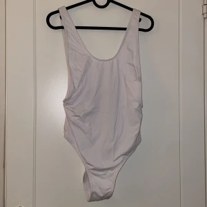 Baddräkt/body - Vid baddräkt som också går att använda som body. Hög i skärningen på sidorna vilket formar kroppen. Helt oanvänd med prislappen kvar.  Storlek M men passar också en S 