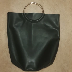 Väska  - Svart skinnimitations väska med förgyllda handtag. Från Lindex. 