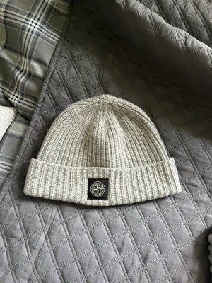 Stone island Mössa - Stone island mössa, stickad ,som är grå och i använt skick. Nypris 1200 kr 