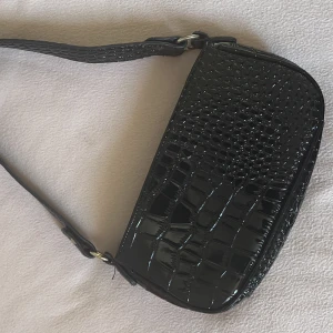 Svart väska - Svart shoulder bag med krokodilmönster. Från ASOS. Kedjan är trasig och går ej att stänga därav priset. 