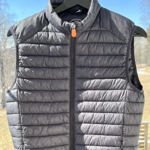 Save The Duck Väst Strlk Small!  - Pris kan diskuteras! Säljer nu min ”Save the duck” väst då jag växt ur den. Västen är svart och i storlek S. En ägare, köptes ny för 1500kr, bra skick. Den är äkta vilket du kan kolla genom att skanna QR koden på insidan av västen. 