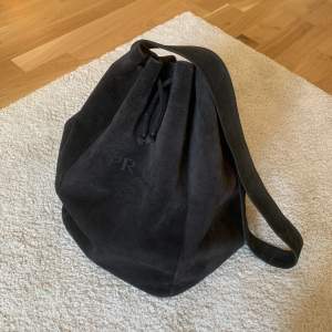 Säljer en bucket väska i mocha material. Färgen är gråsvart och är i  jätte bra skick. Bandet är tillräckligt långt att ha väskan som crossbody om så önskas.