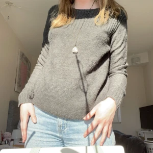 Grå stickad tröja - En tunn stickad tröja perfekt för sommarkvällar. På ena axeln har den 3 guldknappar och den är i nyskick!    