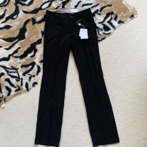 Lågmidjade kostymbyxor  - Säljer mina helt oanvända skitsnygga kostymbyxor från Bruuns Bazaar då de tyvärr är för små för mig. De är lågmidjade och raka i storlek 34. Ordinarie pris: 999kr